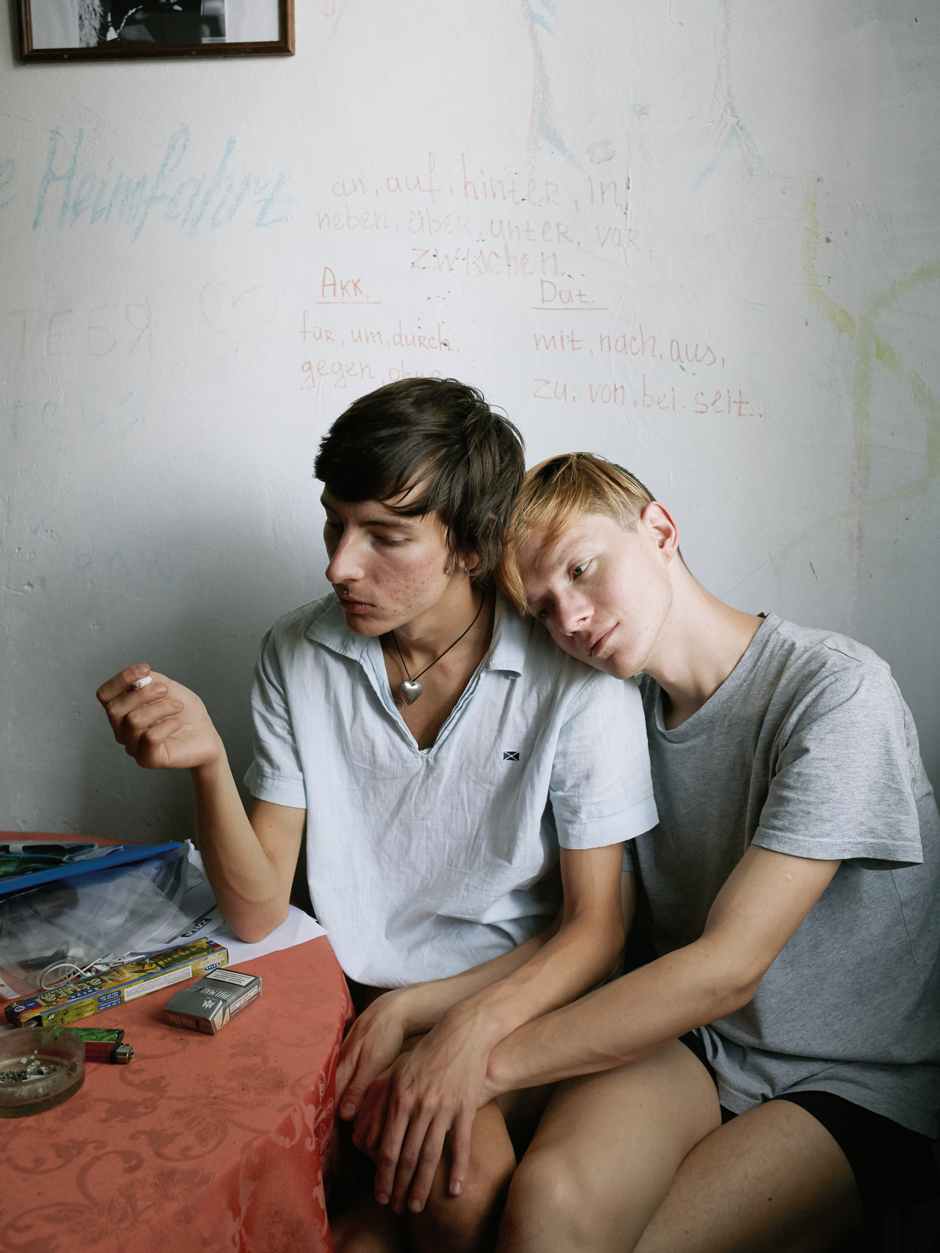 Fotografie zwei junge Männer aneinandergelehnt am Tisch sitzend
